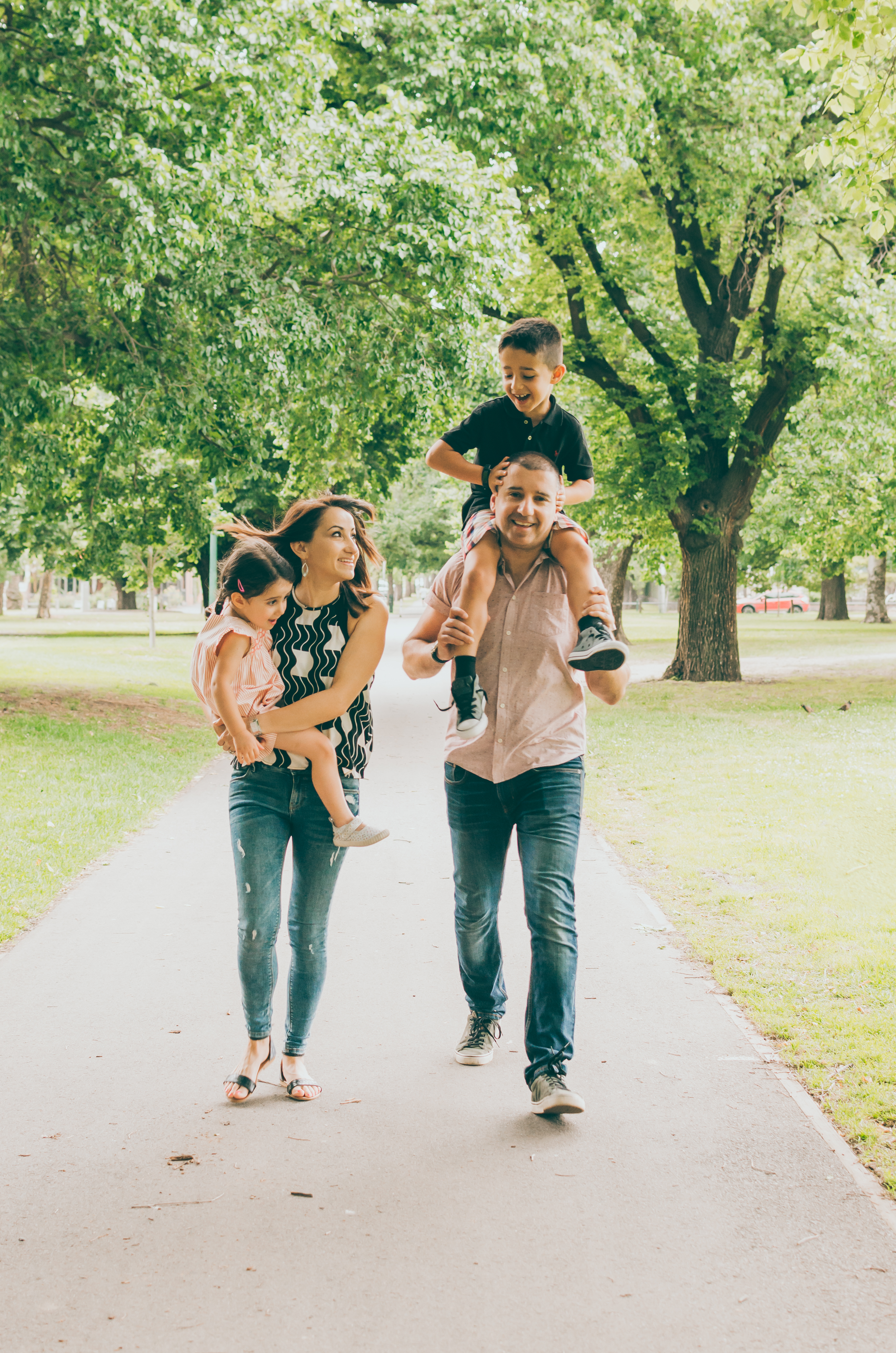 Lifestyle photographer Liyat G Haile documents and captures a happy family walking on tree-lined path, smiling, interacting and connecting at Princes Park, Melbourne, Australia