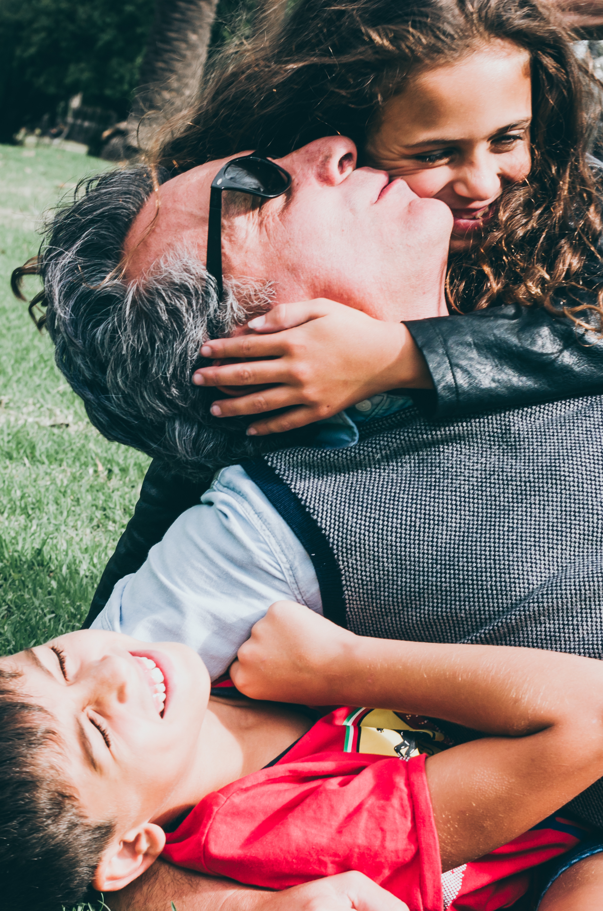 Lifestyle family photographer Liyat G Haile documents and captures a happy father and daughter lying on grass, hugging and kissing interacting and connecting