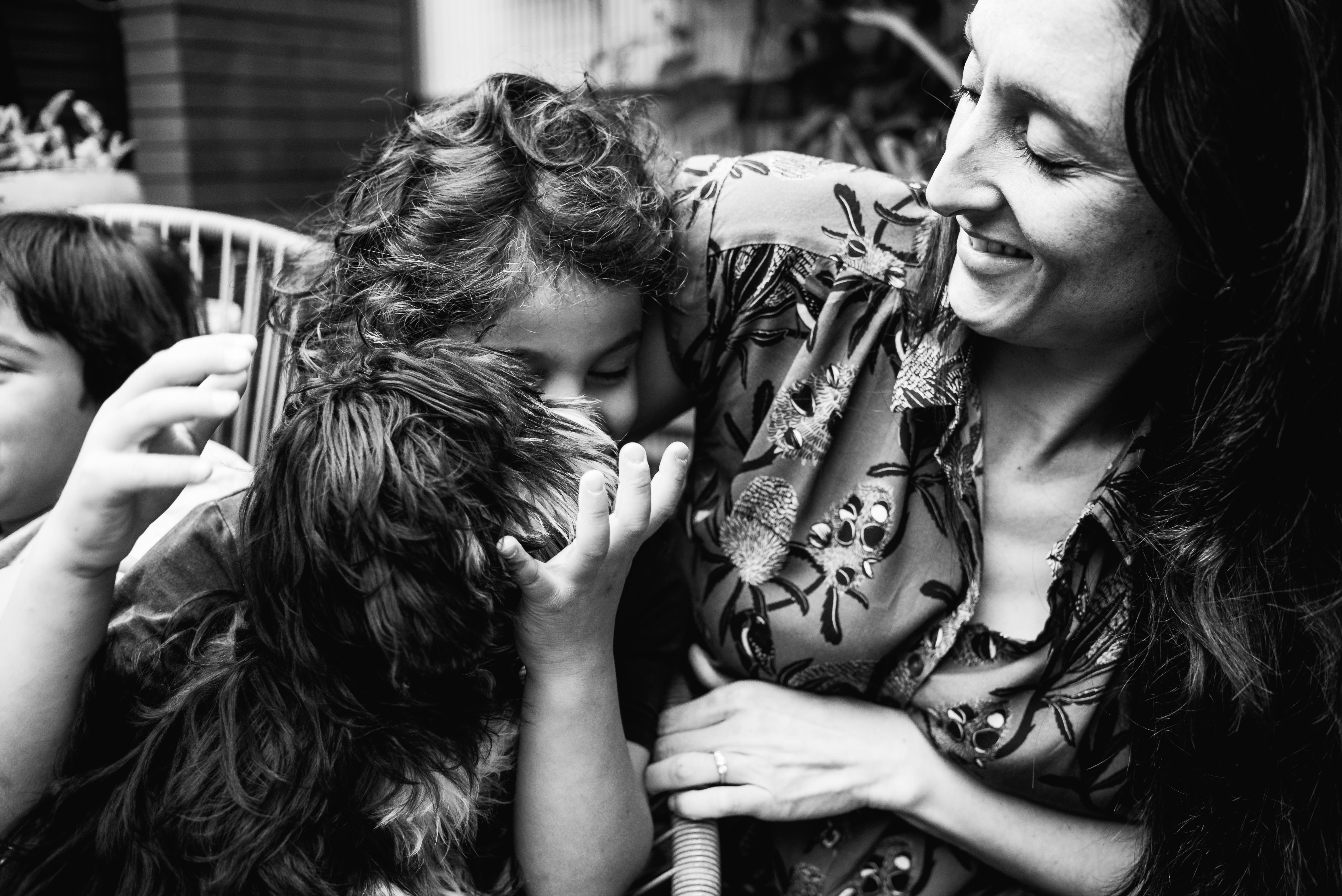 photograph of a boy holding his pet dog and cuddling his mother in Carlton North, Melbourne, Australia