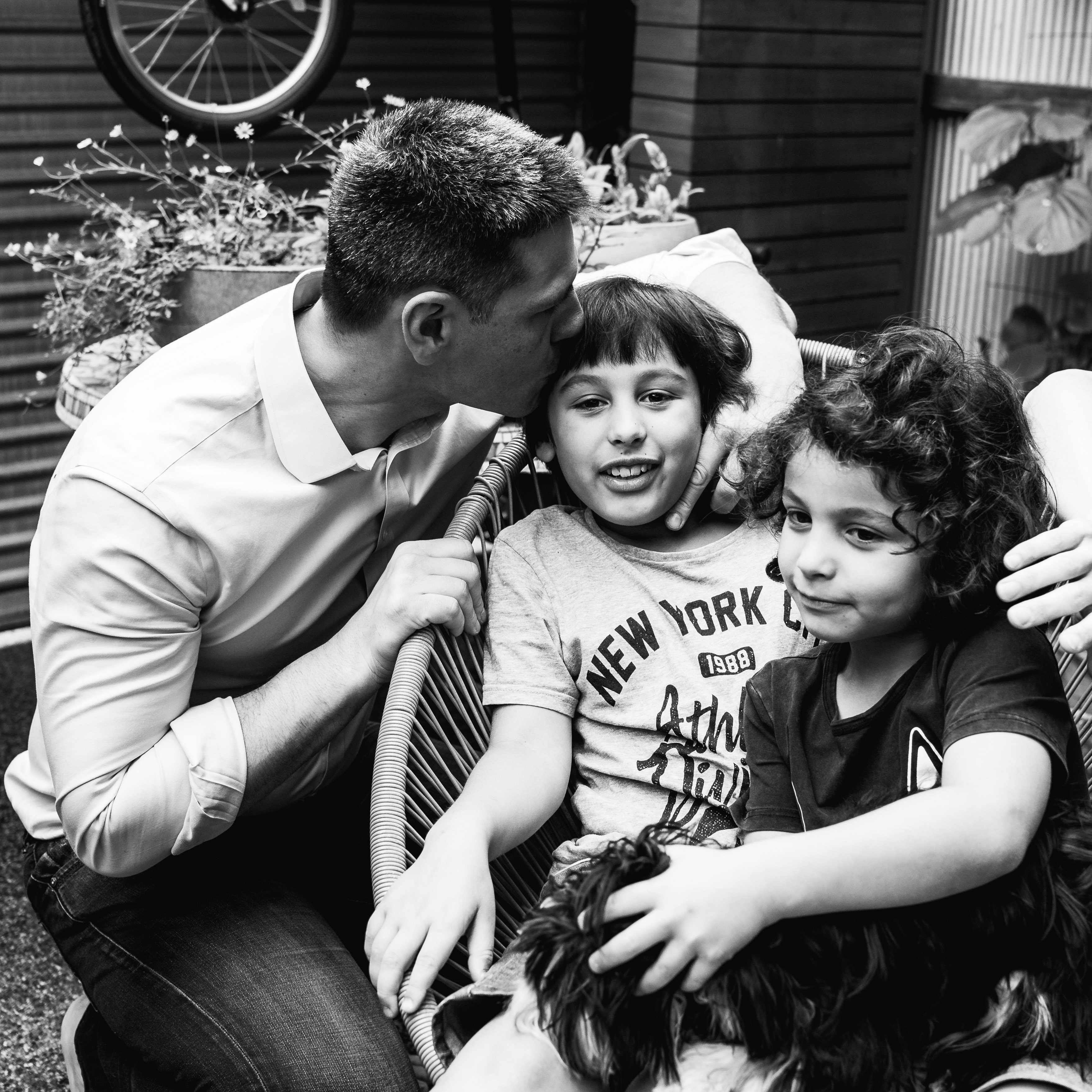 photograph of a father kissing his oldest son in their backyard in Carlton North, Melbourne, Australia