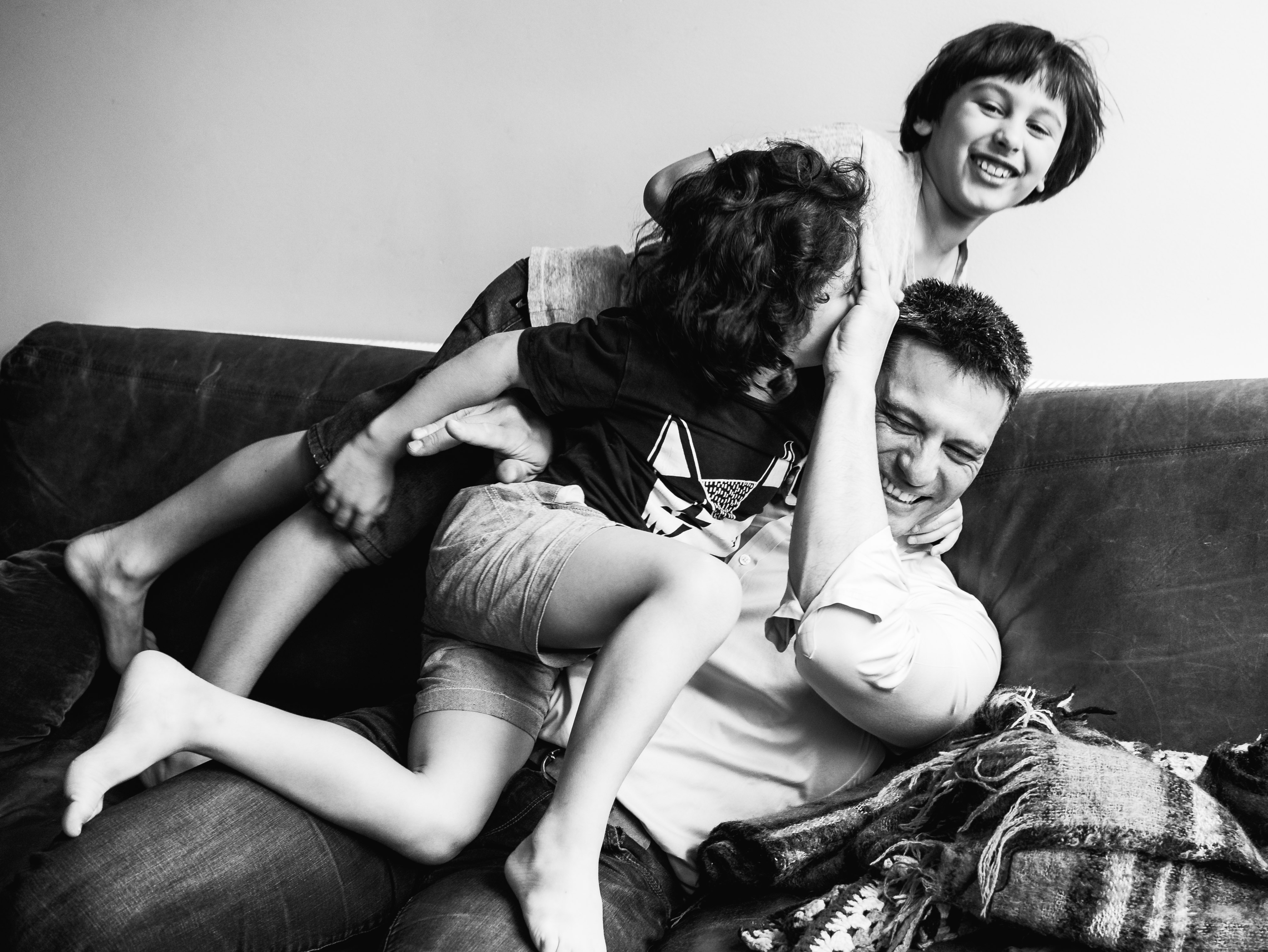 photograph of boys wrestling their father on a couch/sofa in Carlton North, Melbourne, Australia
