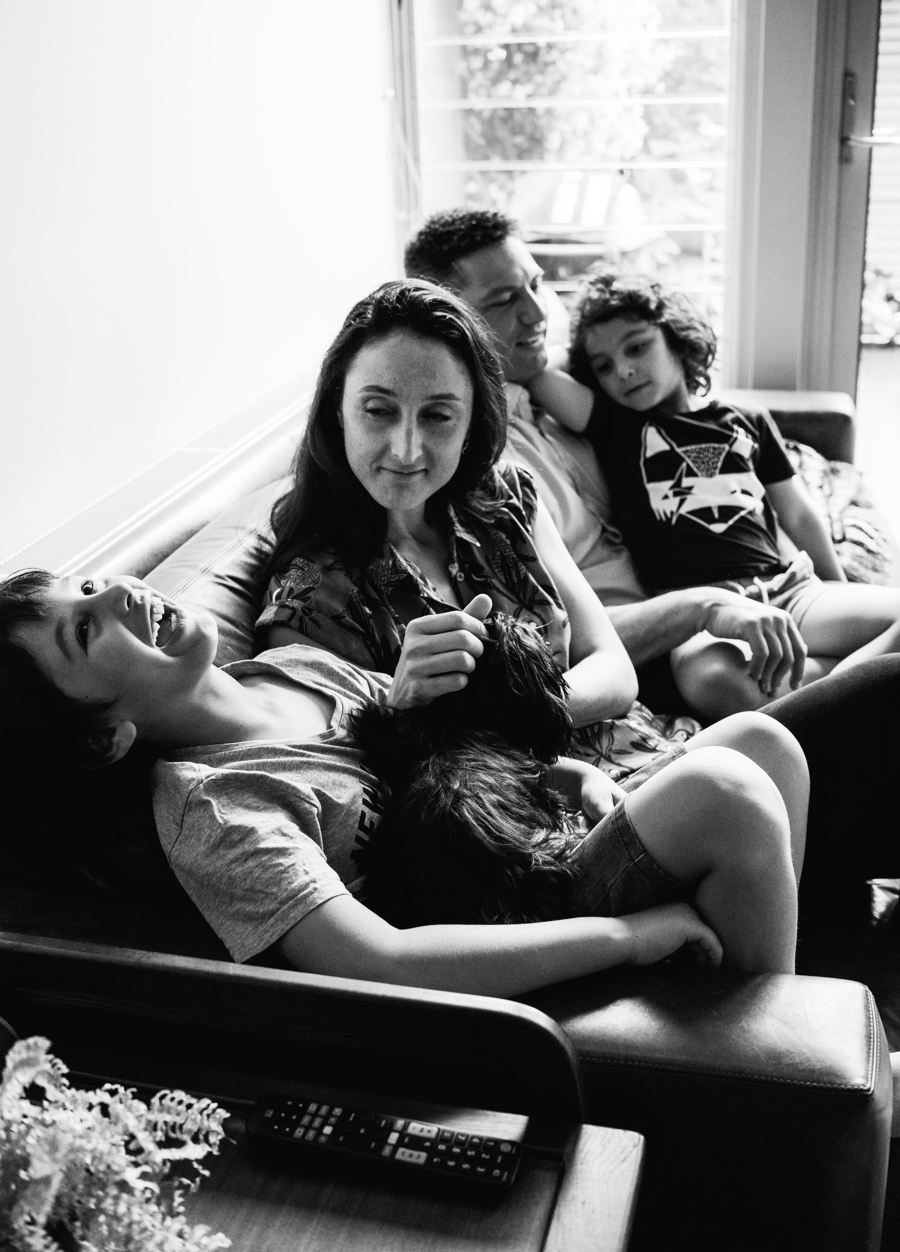 photograph of parents, children and pet sitting on a sofa/couch talking and laughing in Carlton North, Melbourne, Australia