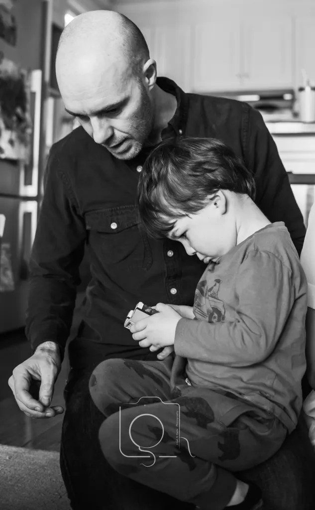 A lifestyle photography session with a Melbourne family in their home. A father interacting with his son who is holding Lego. Photograph by Liyat Haile.