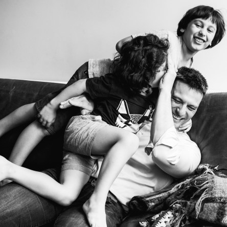 in-home session photograph of boys wrestling their father on a couch/sofa in Carlton North, Melbourne, Australia
