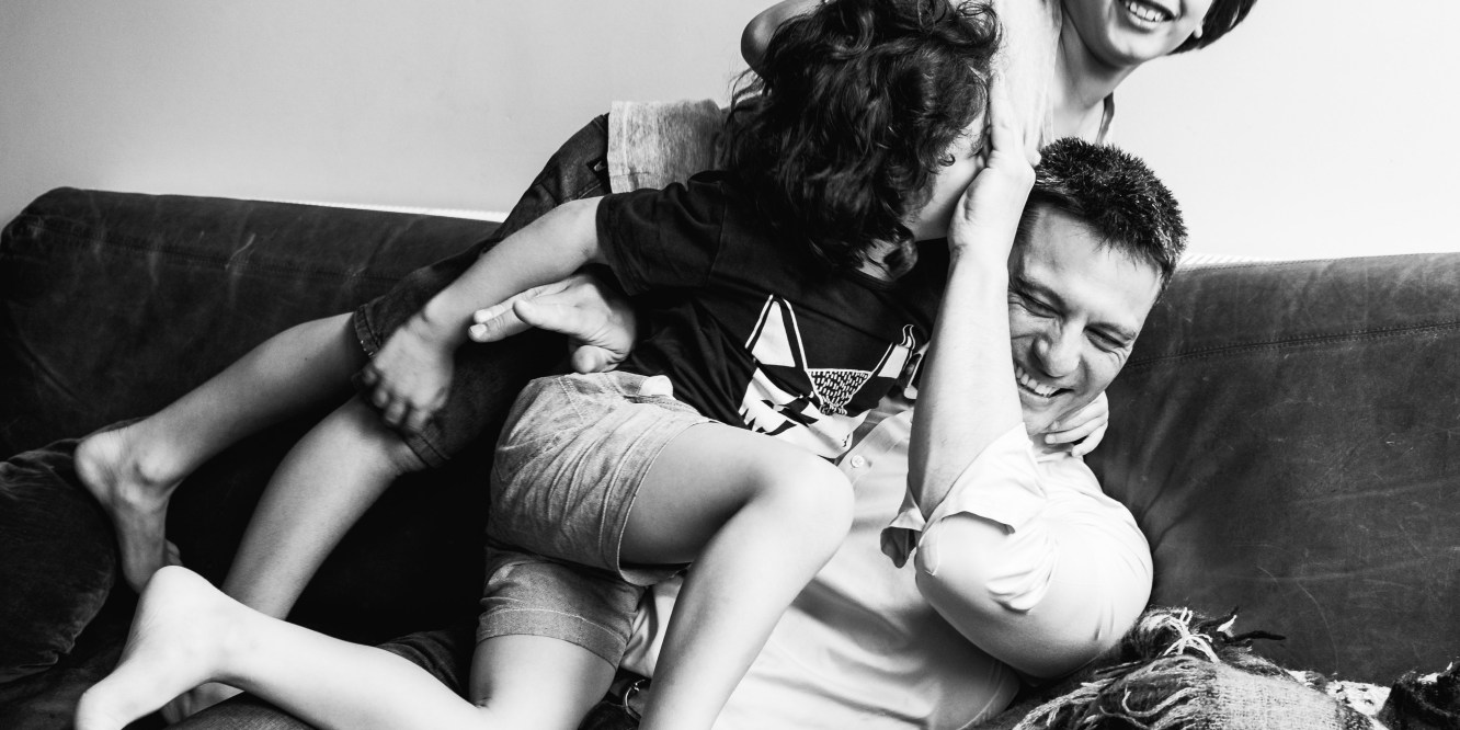 in-home session photograph of boys wrestling their father on a couch/sofa in Carlton North, Melbourne, Australia