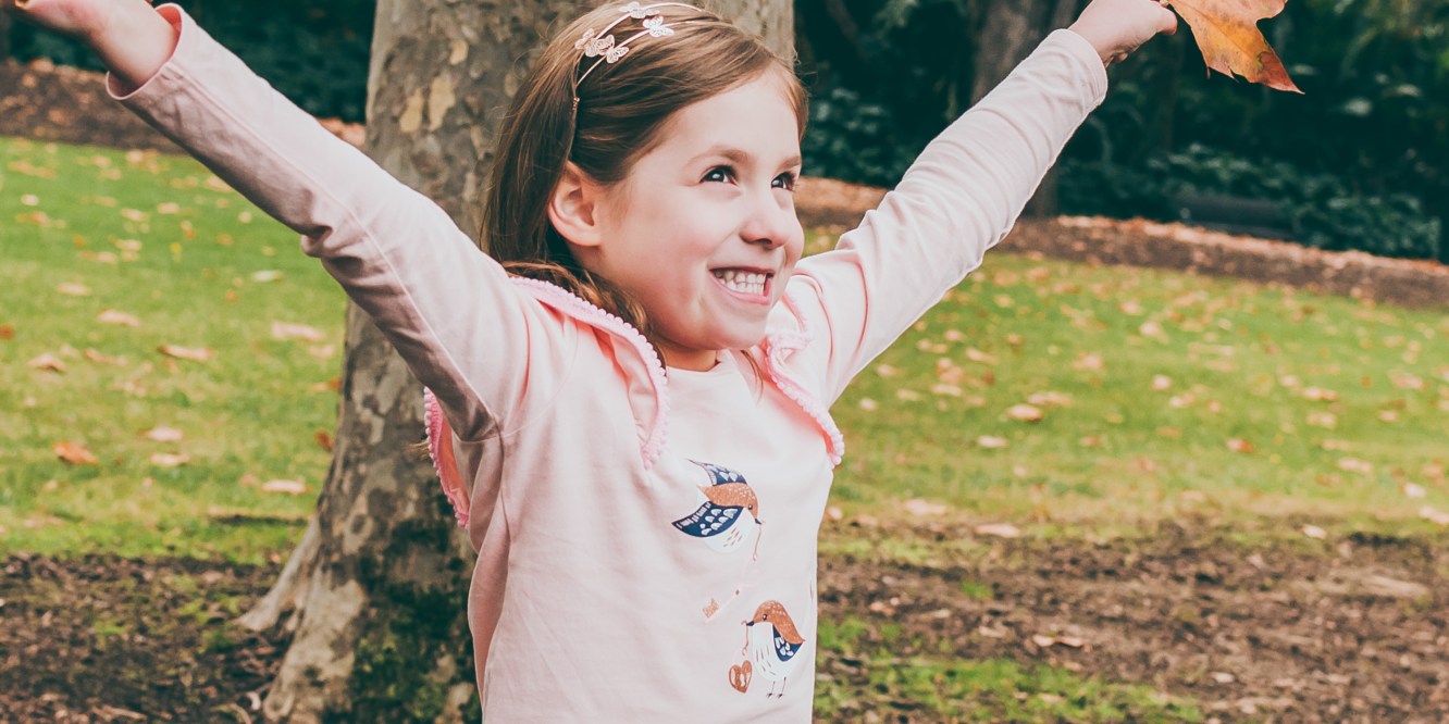 Fun Portrait of a child holding Autumn leaves at Fitzroy Gardens in Melbourne, Australia